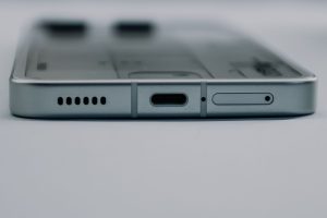 Close-up of a smartphone's bottom edge showing the USB-C charging port, speaker grille and SIM tray