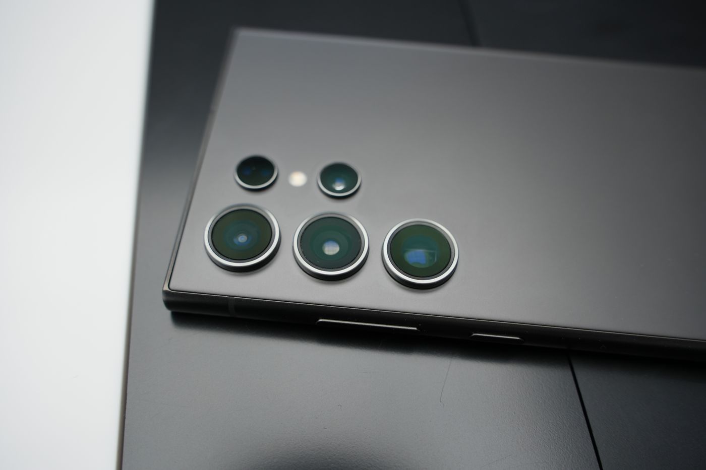 Close view of an Android phone rear camera, five protruding lens rings on black glass