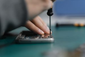 Hand using a precision screwdriver on an opened phone frame with the display removed